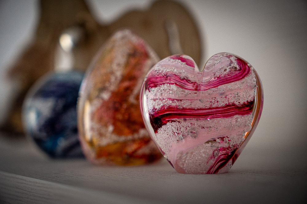 Stuart Wiltshire pink glass heart keepsake, with colourful memorial glass in the background